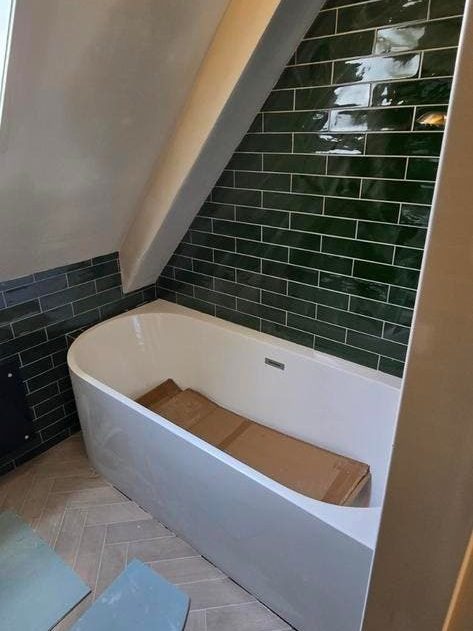 Dezelfde groene badkamer tijdens het werk, het bad nog afgedekt met een plaat