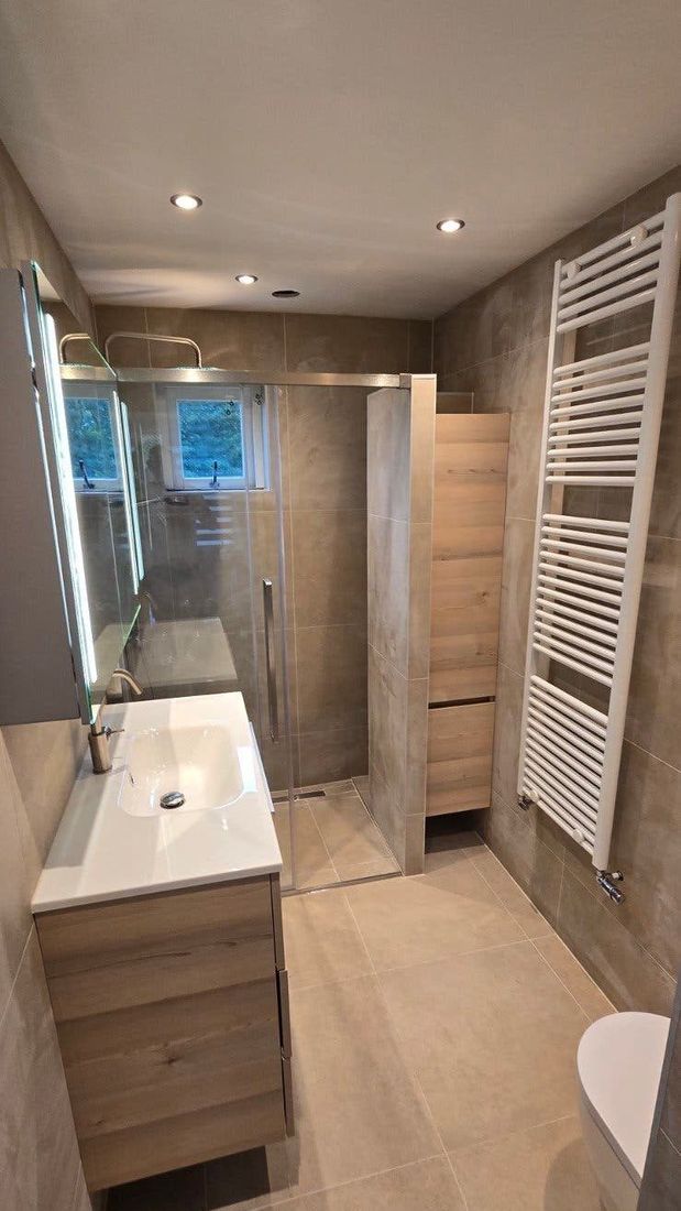 Smalle badkamer met wastafelmeubel, douche en handdoekradiator